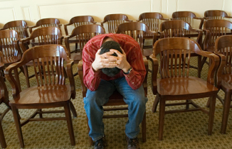 A parent alone in an empty courtroom, head in hands